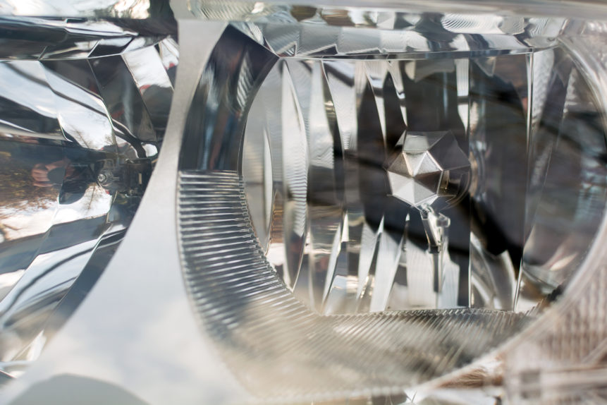 Detalhe de lente e refletores de um farol automotivo